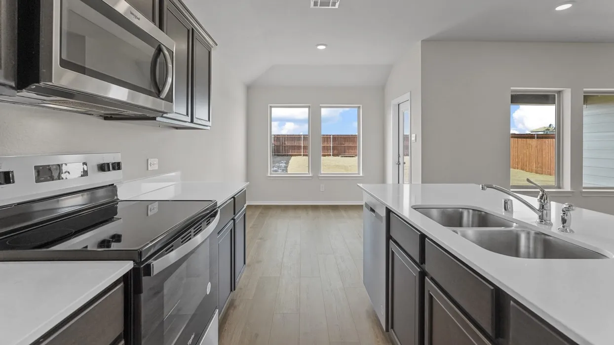 Kitchen featuring dark wood-finish cabinetry, stainless steel appliances, white countertops, and a double basin sink