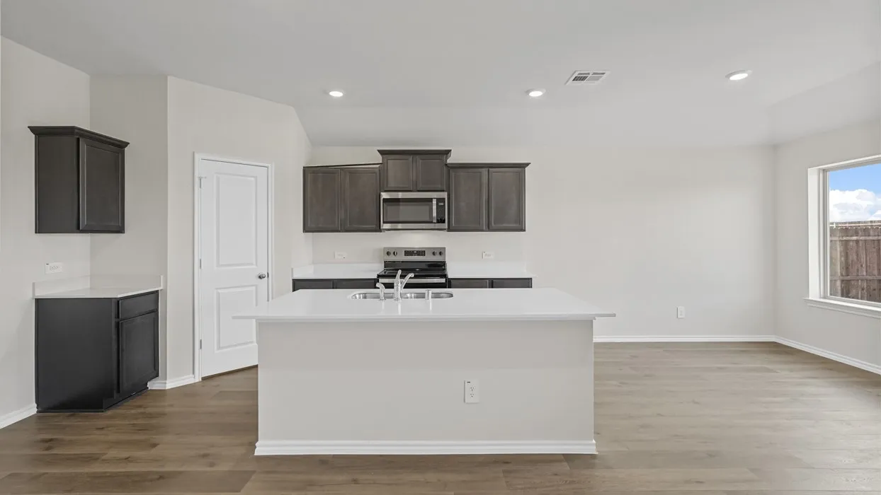 Kitchen with recessed lighting, dark cabinetry, stainless steel appliances, and a central island with a sink