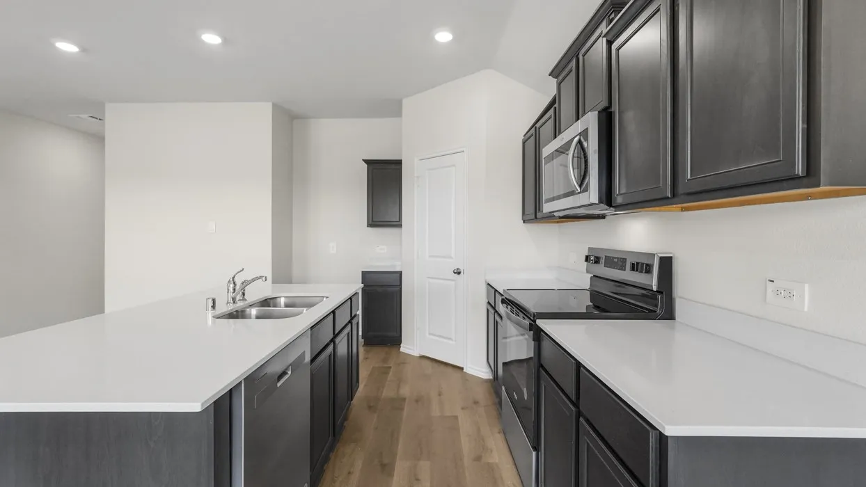Kitchen featuring a double basin sink, stainless steel appliances, dark wood-finish cabinetry, light-toned countertops, and wood-finish flooring