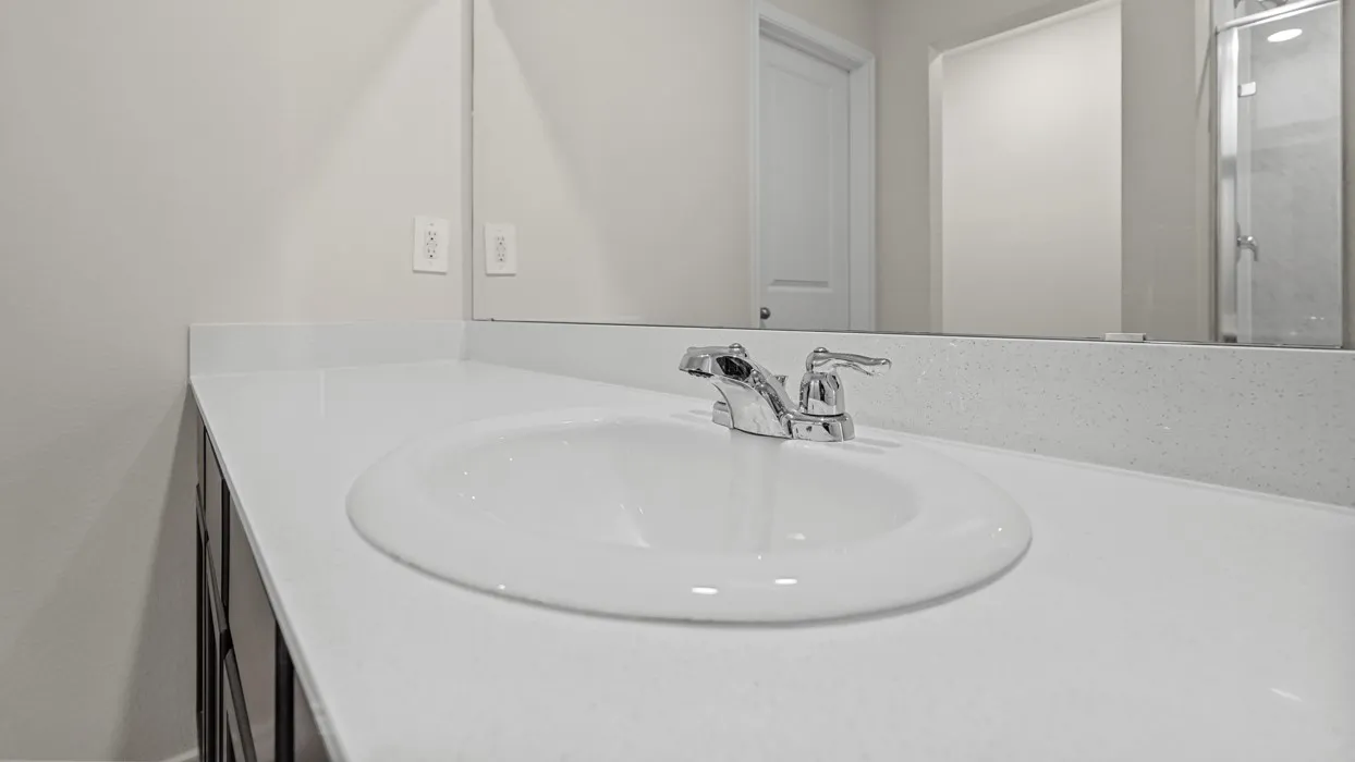 Vanity with an integrated basin, chrome faucet, and expansive wall mirror