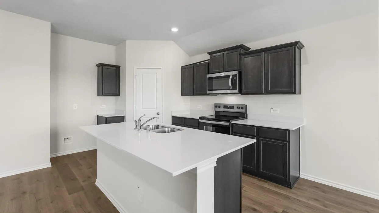 Kitchen featuring a central island with an undermount double basin sink, stainless steel appliances, dark wood-finish cabinetry, white countertops, and wood-finish flooring