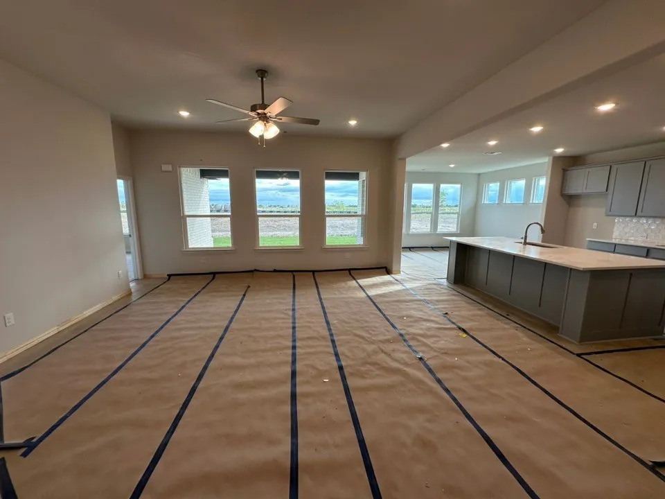 Open-concept living space featuring a spacious kitchen island with a light-toned countertop, recessed lighting, ceiling fan, and multiple windows