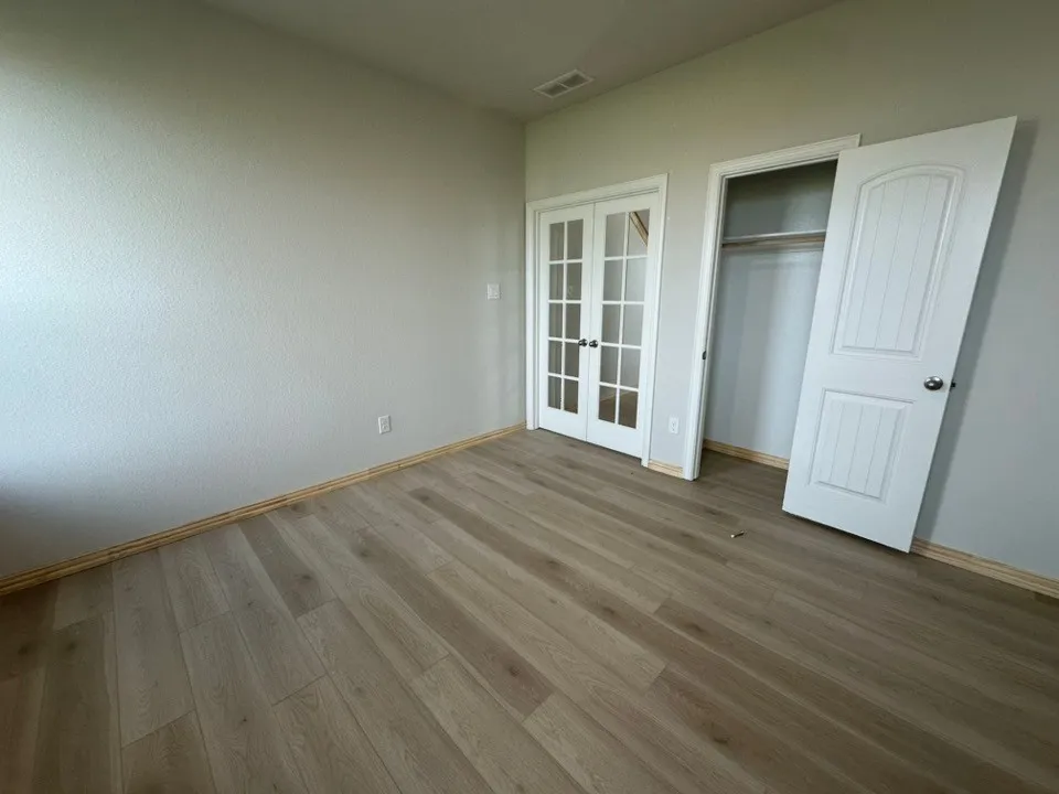 Wood-finish flooring, light gray wall paint, French doors with glass panes, and a closet with a single paneled​​‌​​​​‌​​‌‌​‌‌​​​‌‌​‌​‌​‌​​​‌​​ door