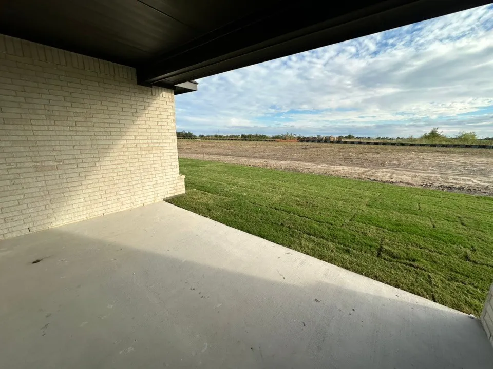 Covered patio with a concrete surface and light-colored brick exterior