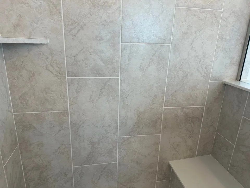 Built-in shower bench, integrated wall niche, and large format wall tile