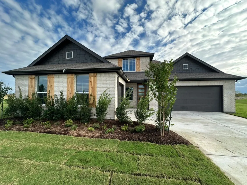 White brick facade with dark shake siding accents, architectural shingle roof, and wood shutters