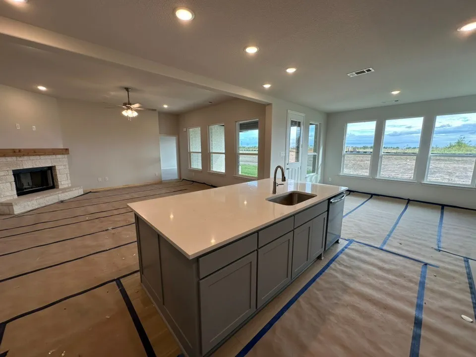 Kitchen island featuring a single-basin sink, stainless steel dishwasher, and light-toned countertop