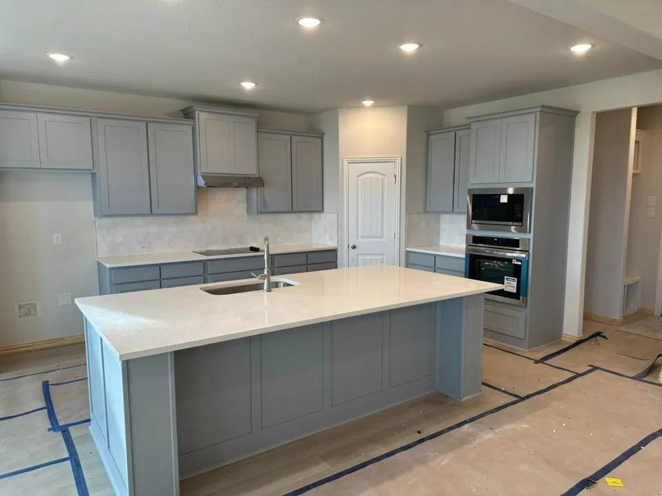Kitchen featuring light gray shaker cabinetry, stainless steel appliances, a center island with sink, recessed lighting, and a patterned tile backsplash