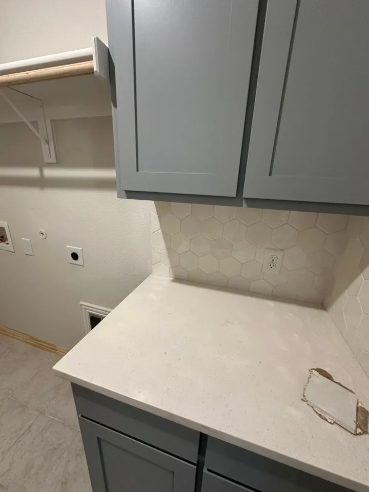 Gray shaker cabinetry with a light-toned countertop and hexagonal tile backsplash