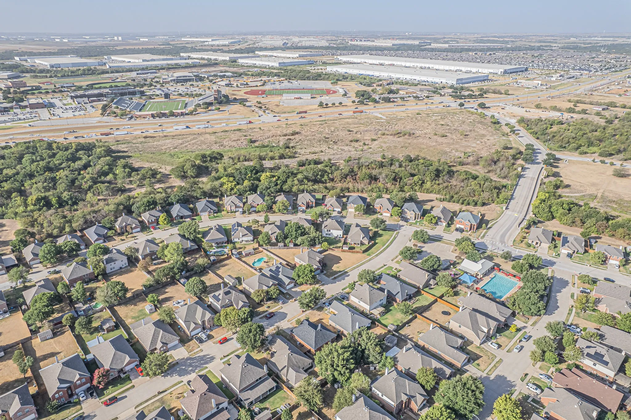 Aerial overview of a residential neighborhood with surrounding Northwest ISD School structures and open land