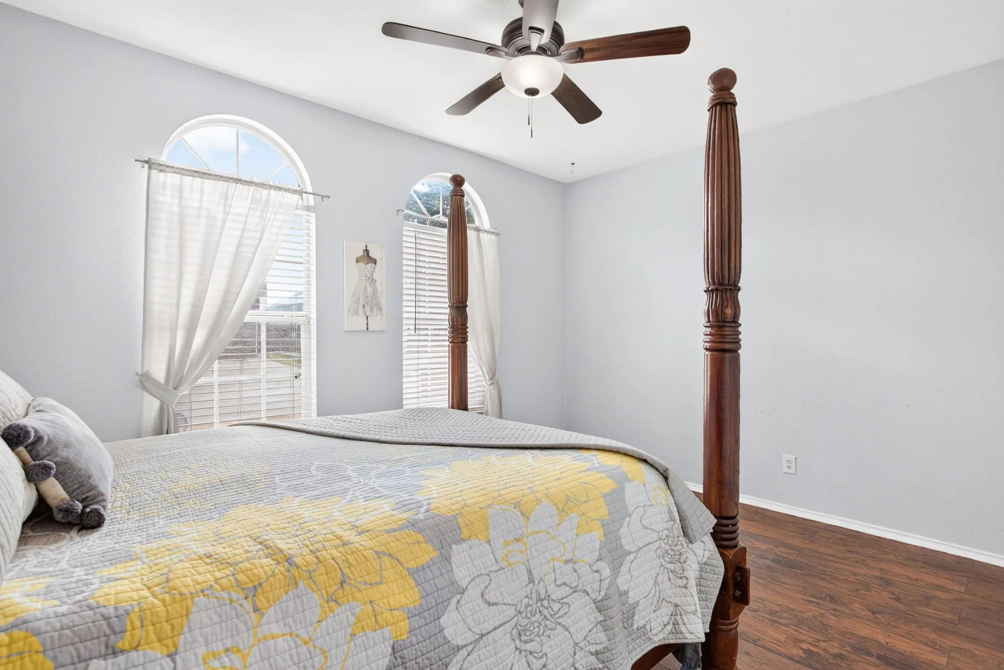 Arched windows with blinds, wood-finish flooring, and a ceiling fan with integrated lighting