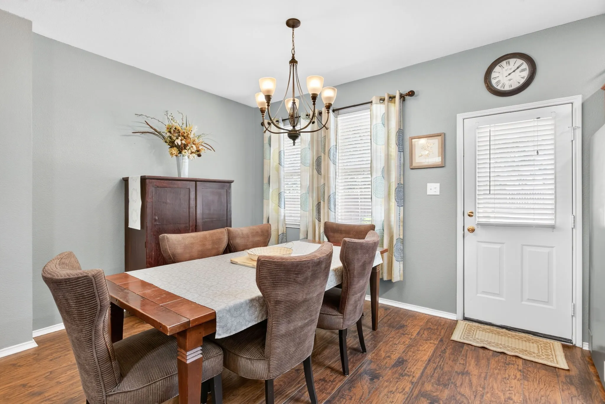Wood-finish flooring, light gray wall paint, and a white paneled door with integrated blinds