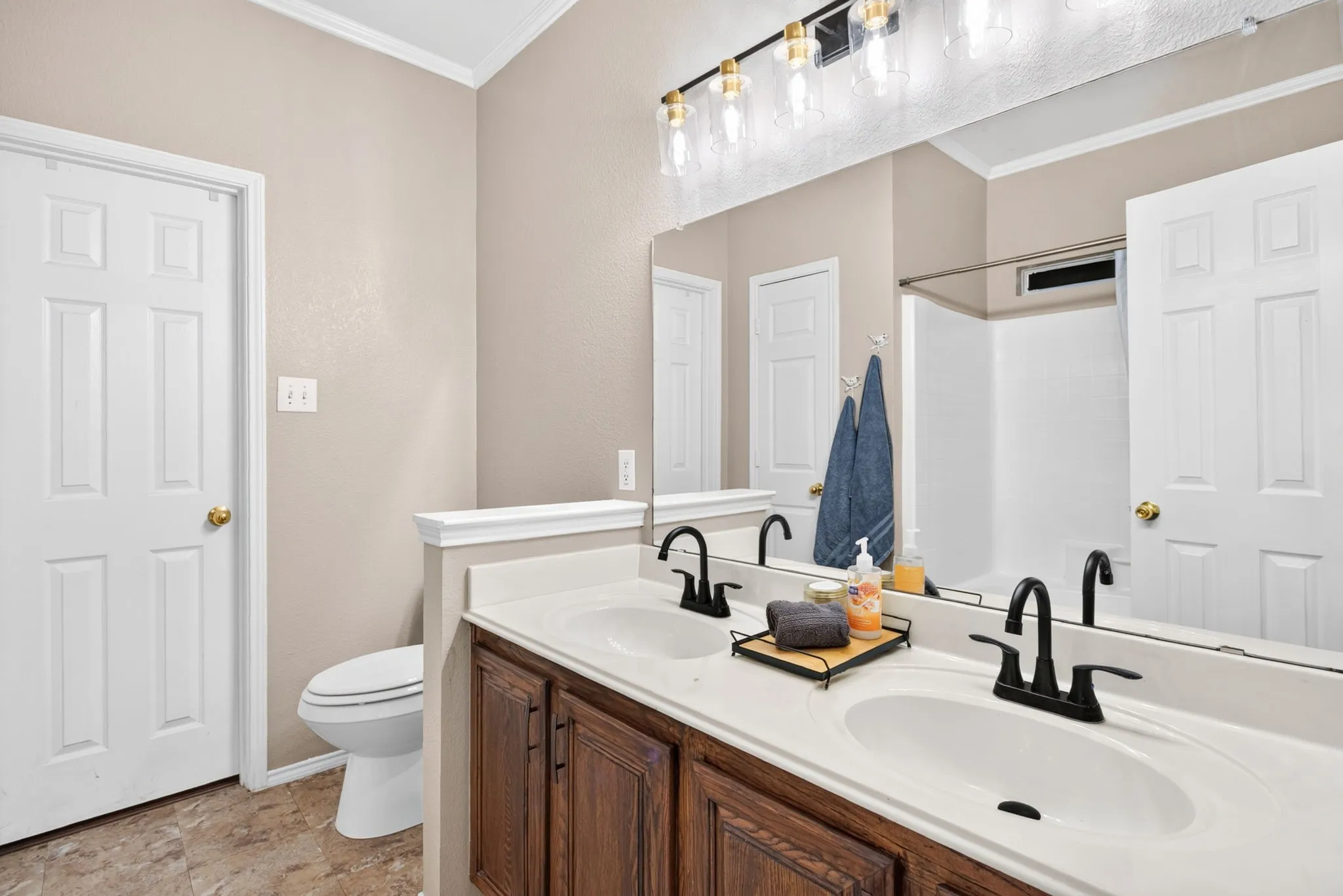 Dual vanity with integrated white sinks, dark wood-finish cabinetry, and matte black fixtures