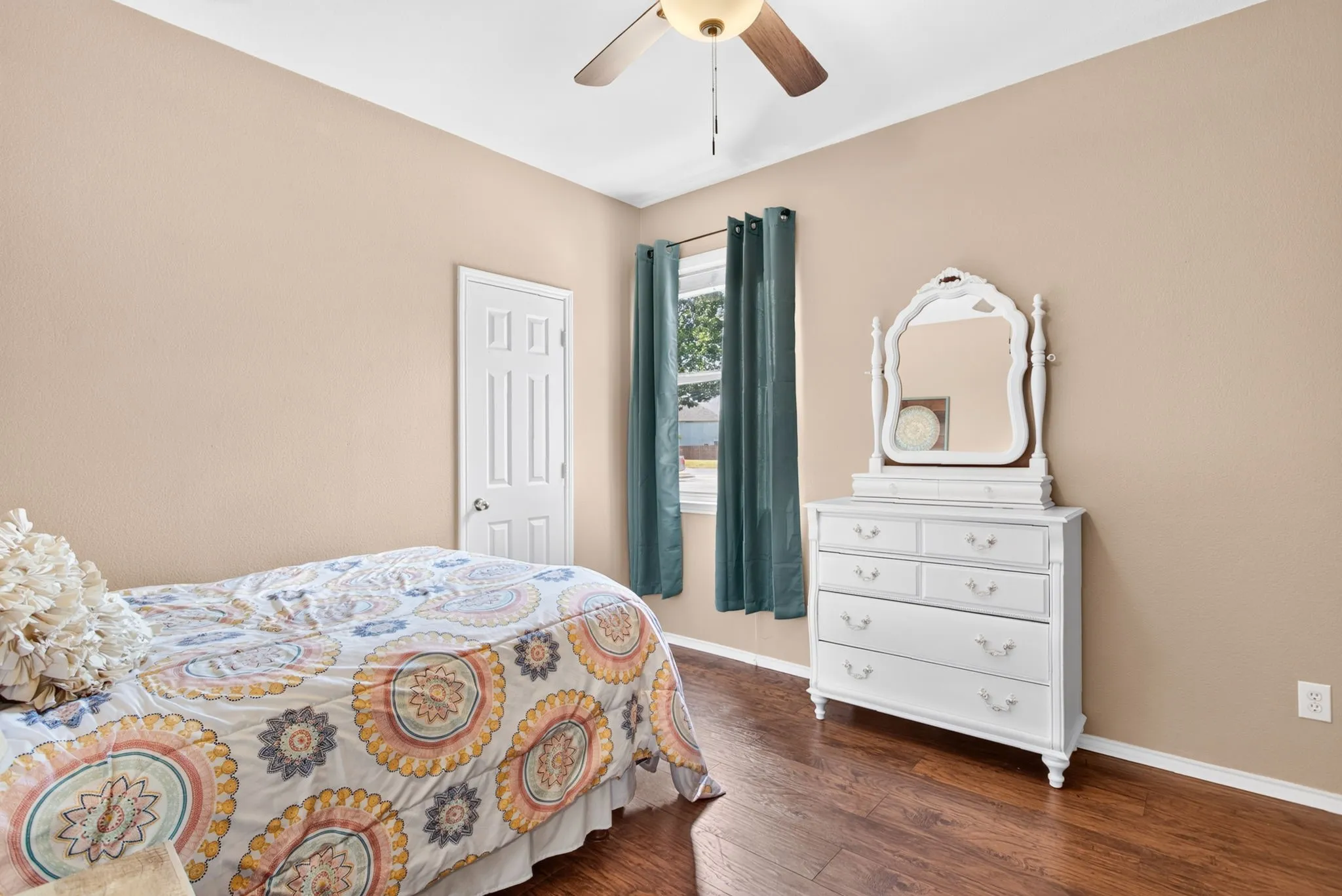 Wood-finish flooring, ceiling fan with integrated lighting, window with drapes, and a paneled interior door