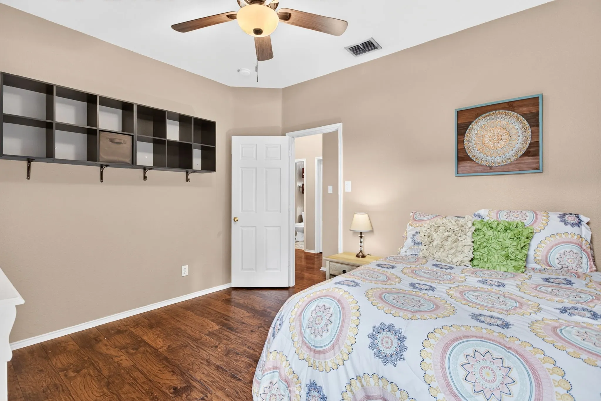 Wood-finish flooring, built-in shelving, ceiling fan with integrated lighting, and a paneled door