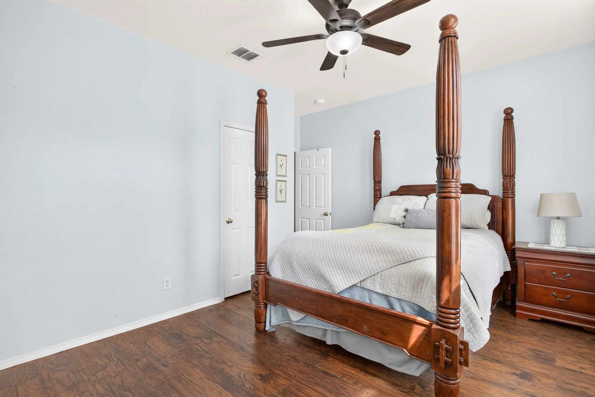 Wood-finish flooring, ceiling fan with integrated lighting, and a paneled interior door