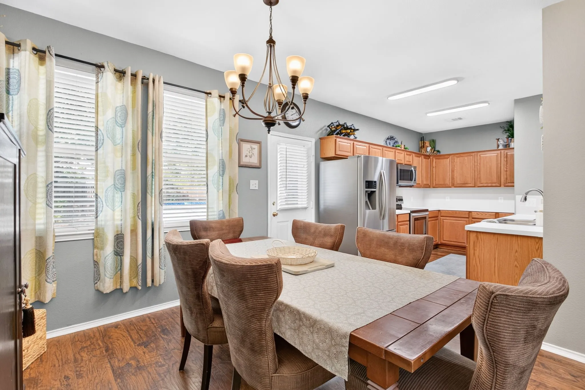 Wood-finish flooring, recessed lighting, ceiling-mounted chandelier, wood cabinetry, and stainless steel appliances