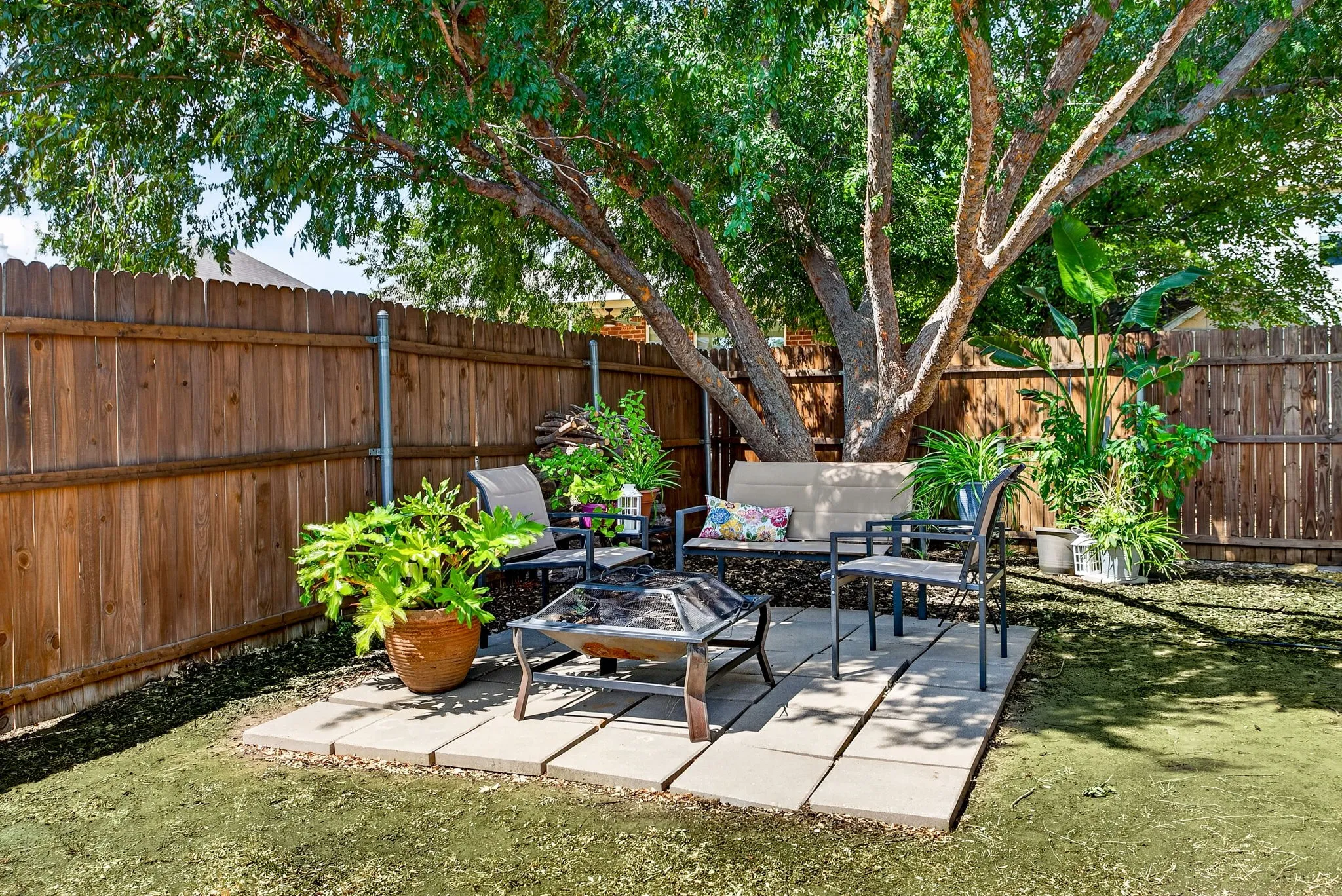 Expansive outdoor space featuring a wood fence, mature trees, and a paver patio