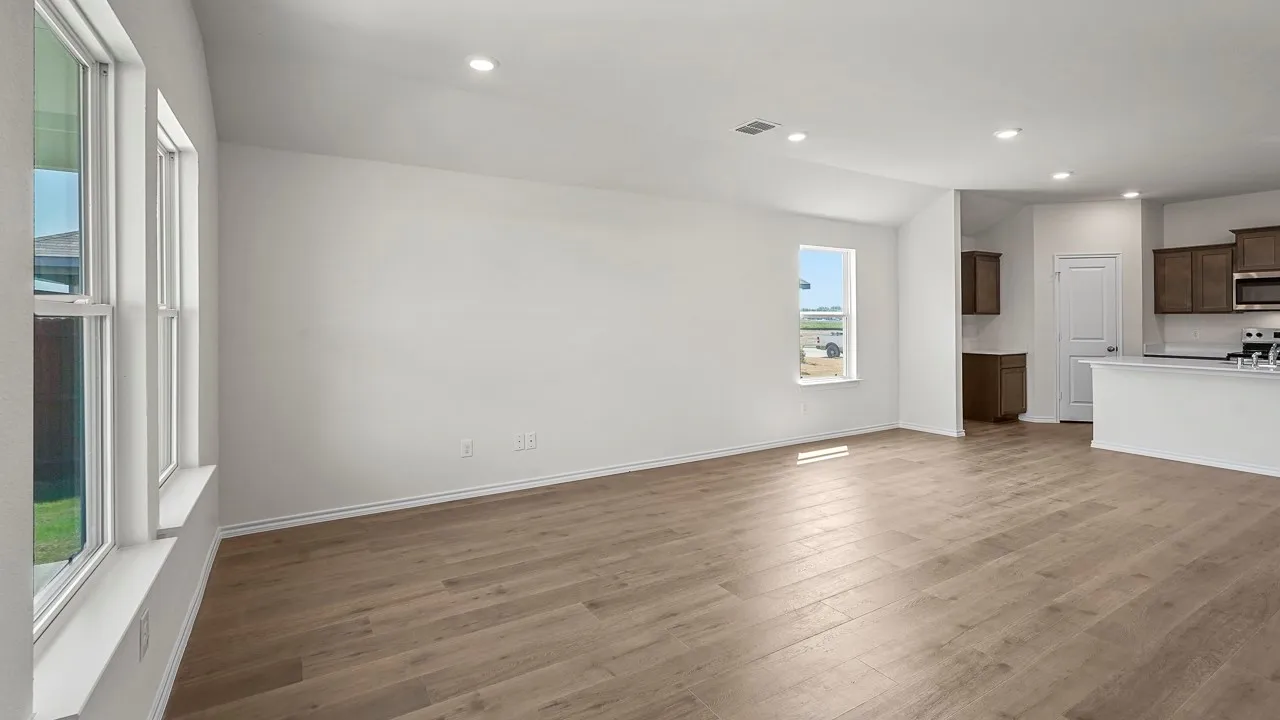 Expansive open concept living area with wood-finish flooring, vaulted ceiling, and recessed lighting