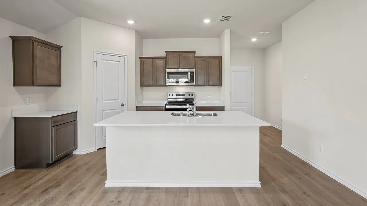 Open-concept kitchen featuring an expansive central island, wood-finish flooring, recessed lighting, and stainless steel appliances