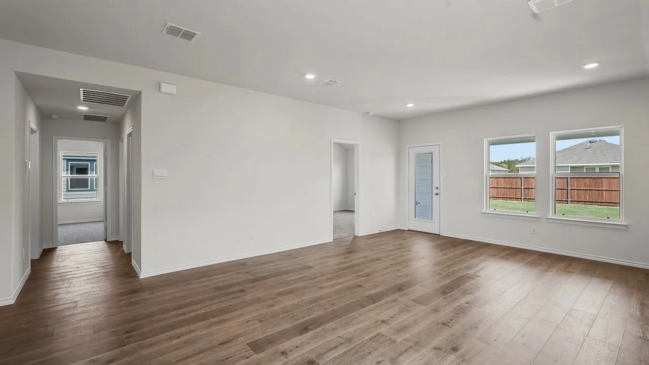 Expansive living area featuring wood-finish flooring, recessed lighting, multiple windows, and a glass-paneled door