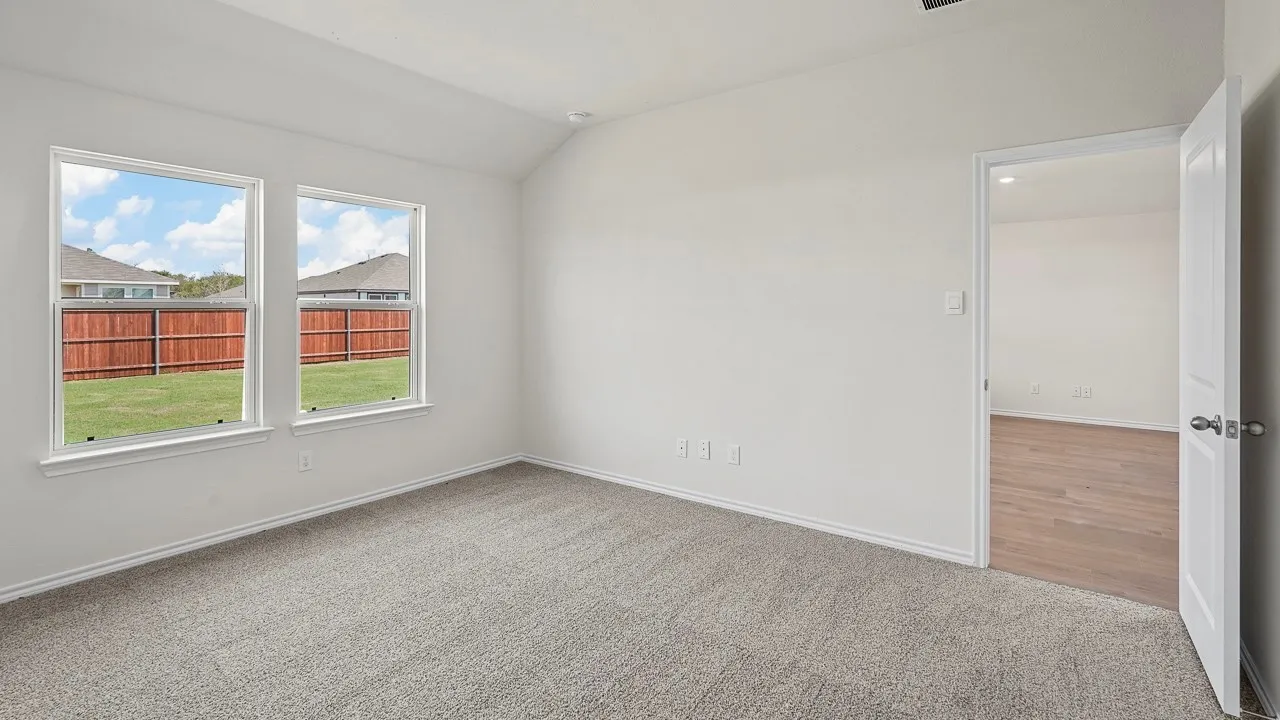 Vaulted ceiling, two double-hung windows, light gray carpeting, neutral wall paint, and a white interior door