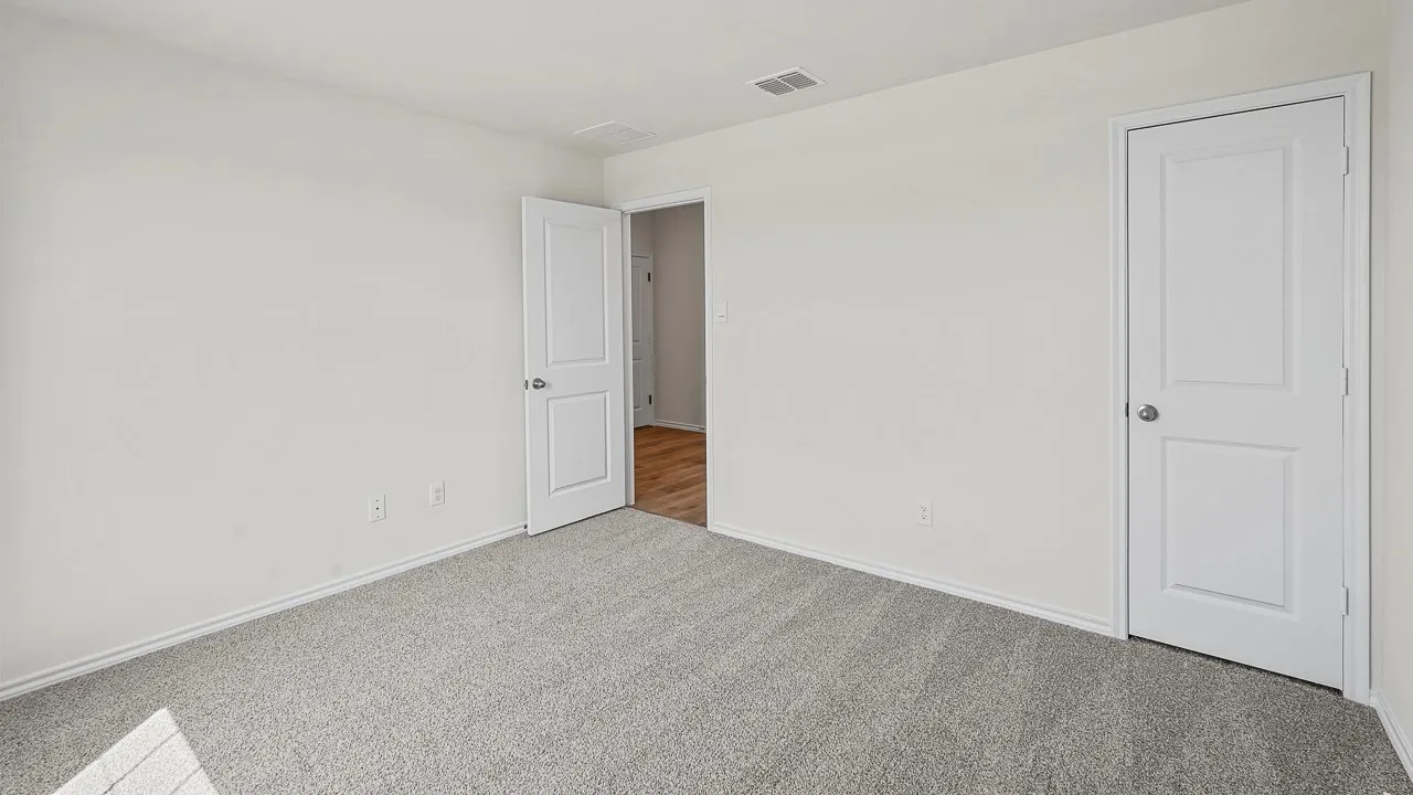 Neutral wall color, grey carpet, white trim, white panel doors, and wood-finish flooring visible through doorway