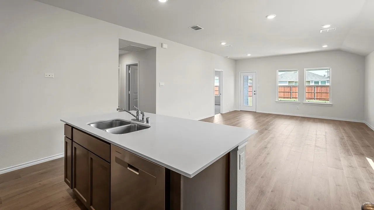 Kitchen island with a double basin sink, light-toned countertop, and integrated dishwasher