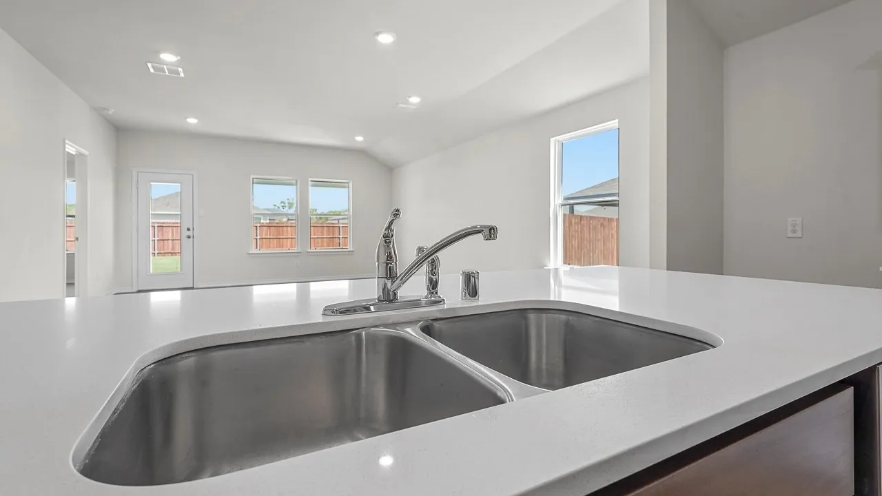 White solid surface countertop with an undermount double basin sink and a chrome pull-down faucet