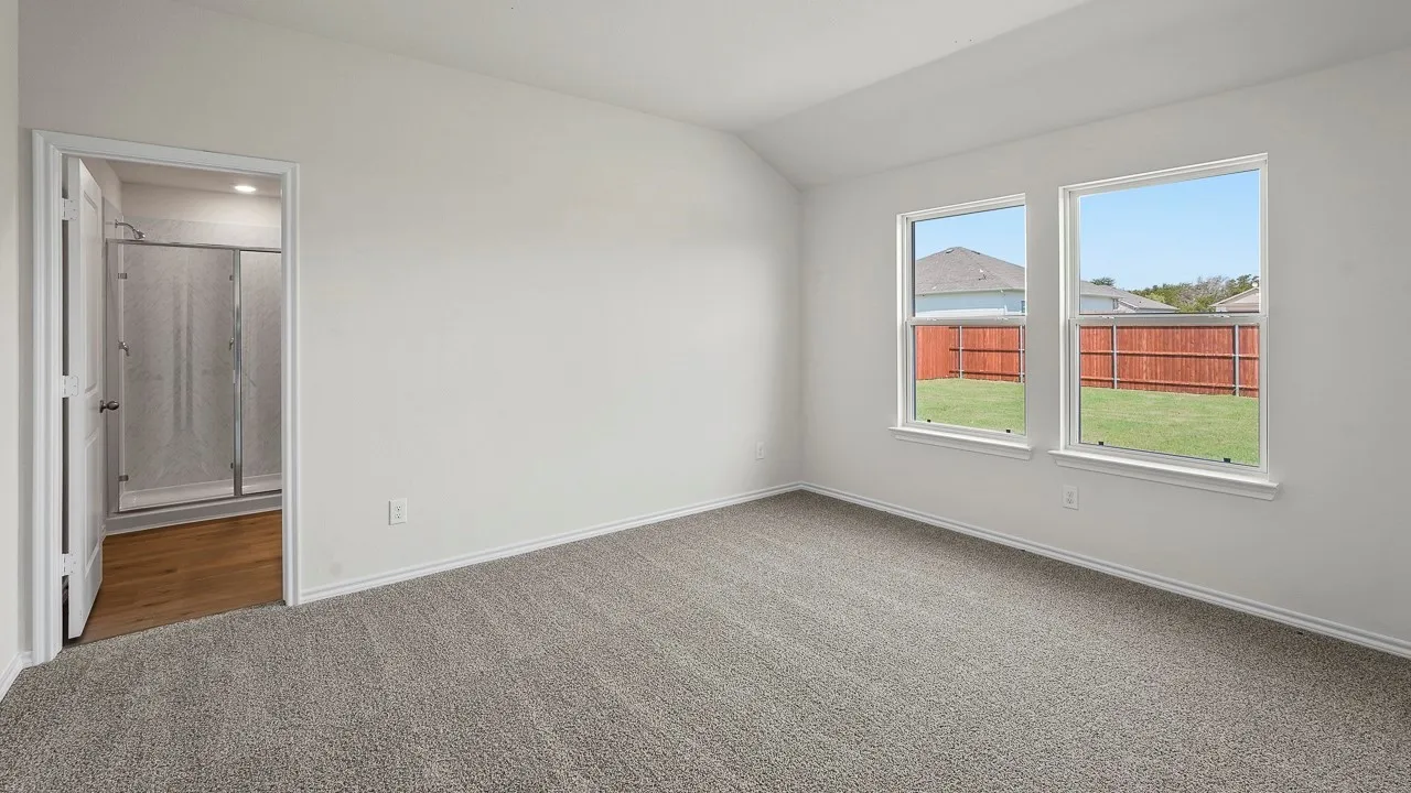 Neutral-toned carpeting, white walls, two double-hung windows, and a vaulted ceiling