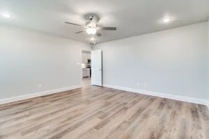 Wood-finish flooring, ceiling fan, recessed lighting, and a white interior door