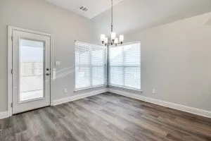 Vaulted ceiling with an attached chandelier, wood-finish flooring, and multiple windows with blinds