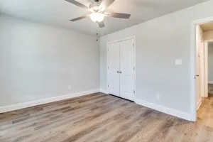 Expansive room featuring wood-finish flooring, light gray wall paint, and a ceiling fan with integrated lighting