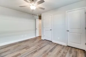 Wood-finish flooring, ceiling fan with light fixture, and paneled interior doors