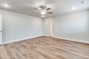 Spacious room featuring wood-finish flooring, recessed lighting, and a ceiling fan with light fixture