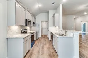 Kitchen with light-toned cabinetry, stainless steel appliances, granite countertops, and wood-finish flooring