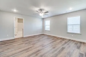 Spacious room featuring wood-finish flooring, recessed lighting, ceiling fan, and multiple windows with blinds