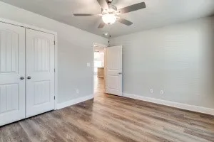 Wood-finish flooring, white paneled doors, ceiling fan with integrated lighting, and light-colored walls