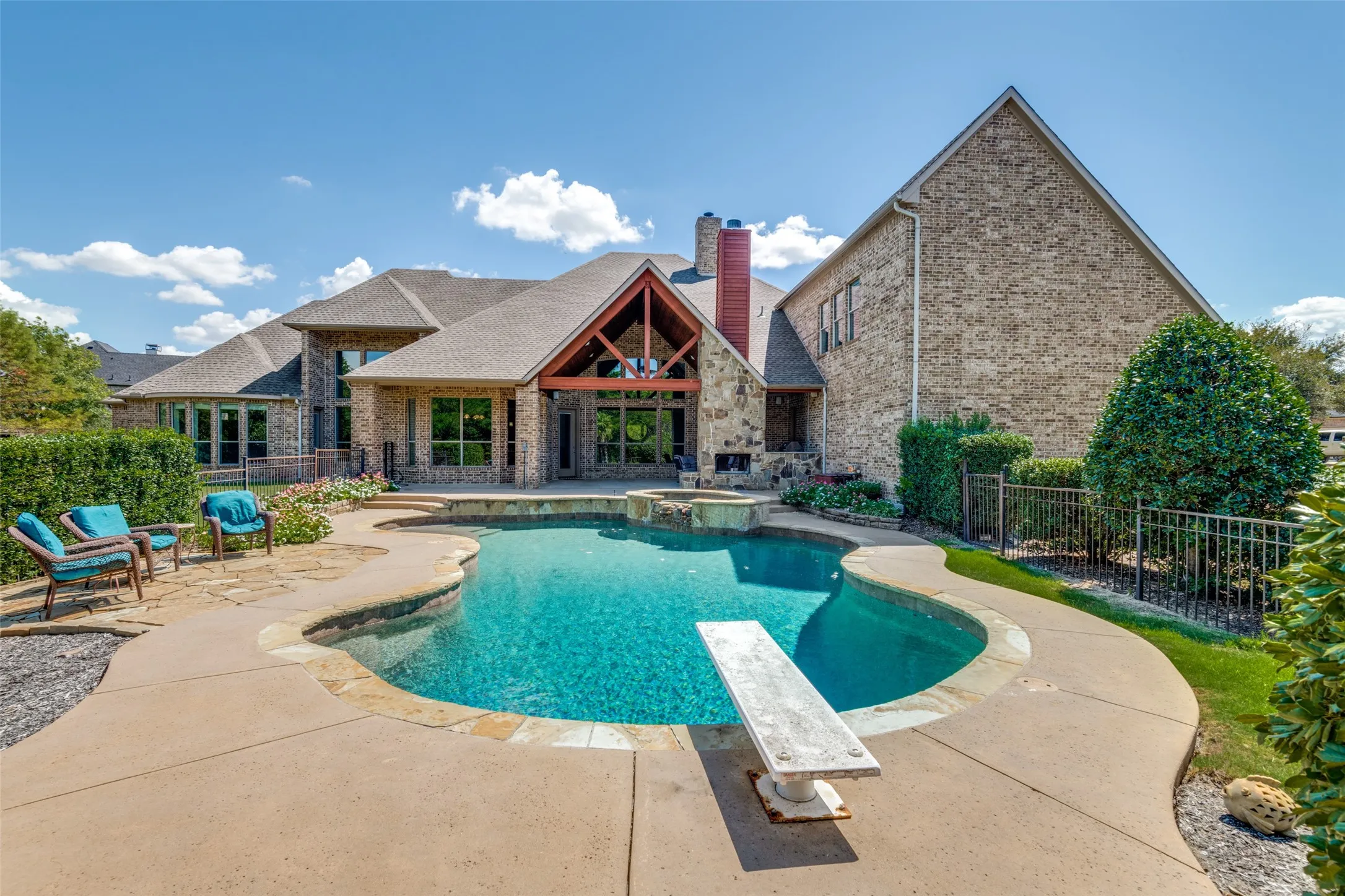 Expansive backyard with a curved swimming pool, diving board, and stone coping