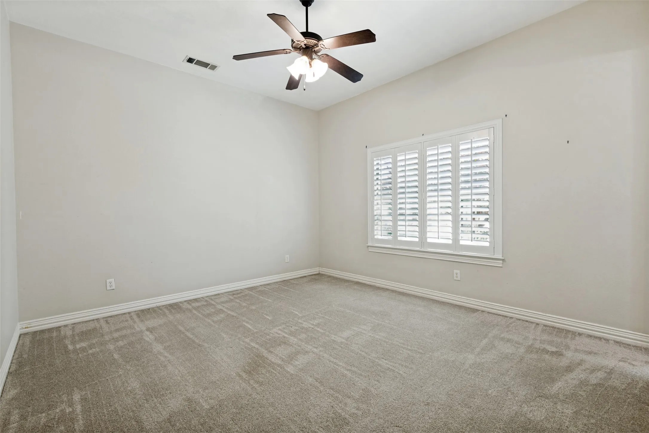 Vaulted ceiling featuring a ceiling fan with integrated lighting, window with plantation shutters, and light-toned carpeting