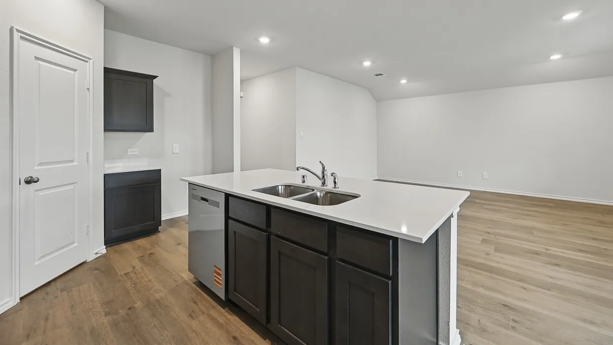 Kitchen island with integrated double basin sink, white countertops, dark wood-finish cabinetry, and wood-finish flooring