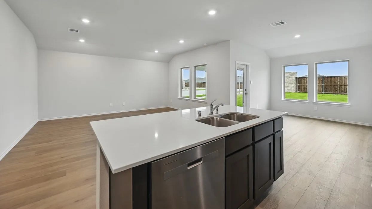 Kitchen island with a white countertop and dark cabinetry, stainless steel dishwasher, and a double basin sink