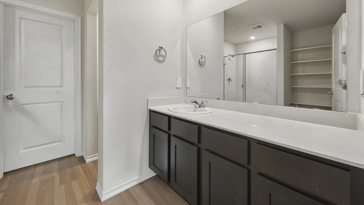Vanity featuring a single sink, light-toned countertop, and dark base cabinetry