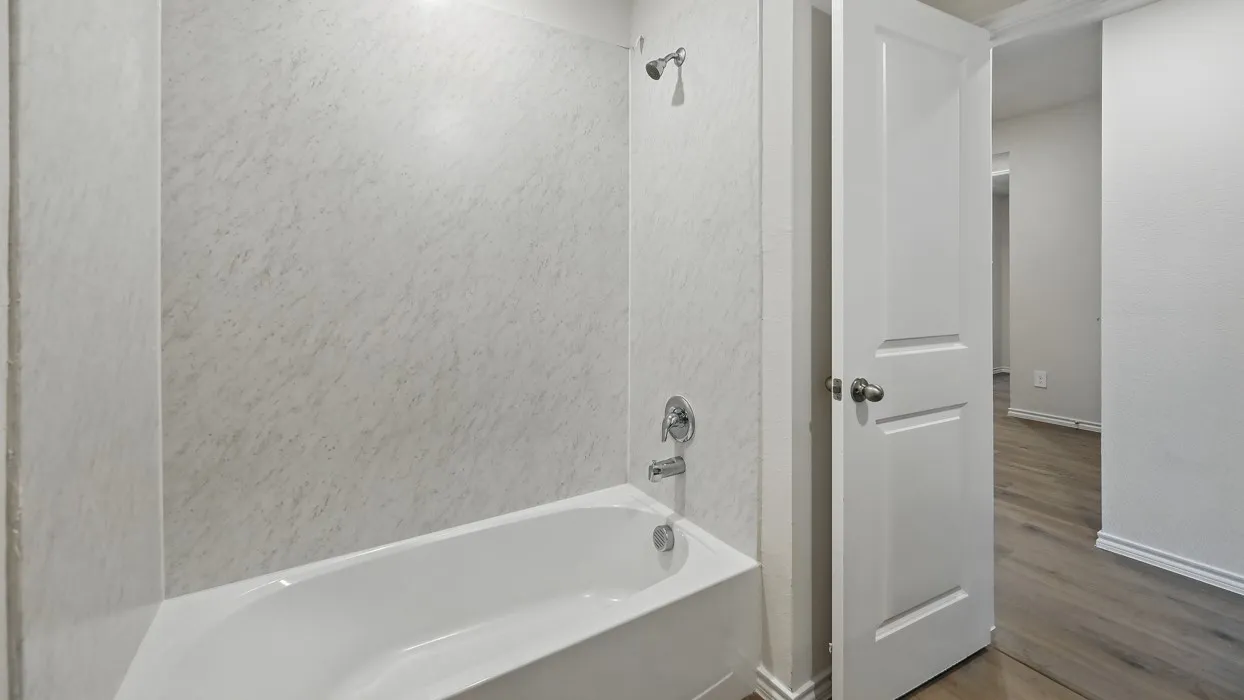 White bathtub and shower surround with chrome fixtures