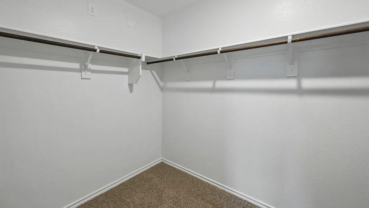 Carpeted walk-in closet with white walls and dual-level hanging rods