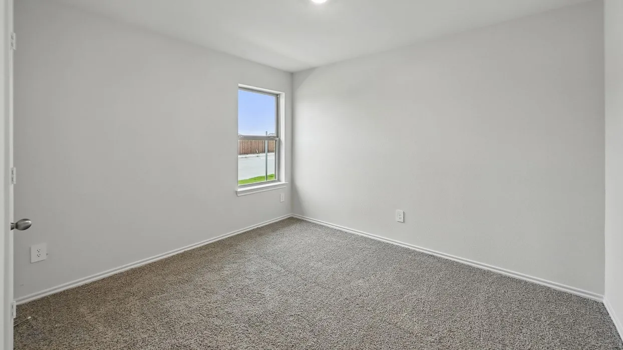 Carpeted flooring, single pane window, overhead lighting, door with knob hardware, and white wall finishes