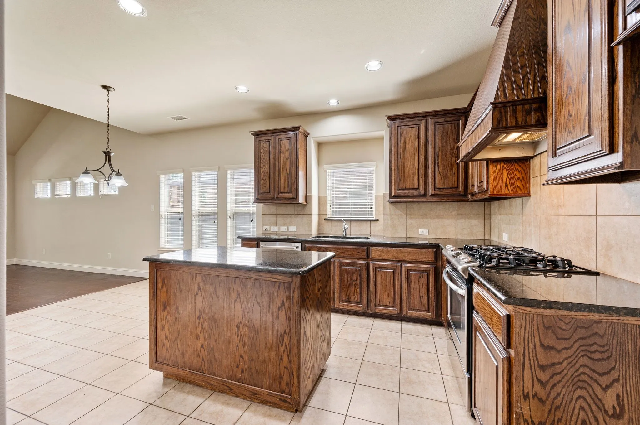 Kitchen featuring dark wood cabinetry, a central island with a dark countertop, tile flooring, and stainless steel appliances
