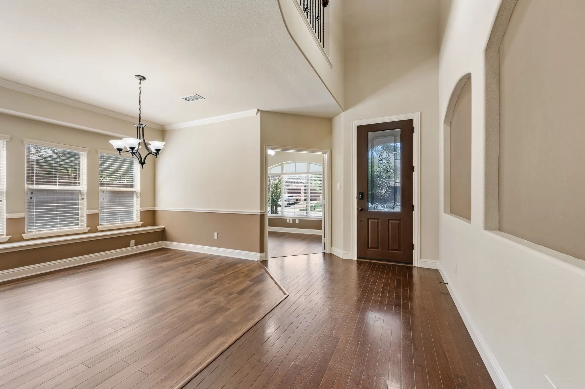 Hardwood-finish flooring throughout, distinct two-tone wall treatment, crown molding, and a chandelier lighting fixture