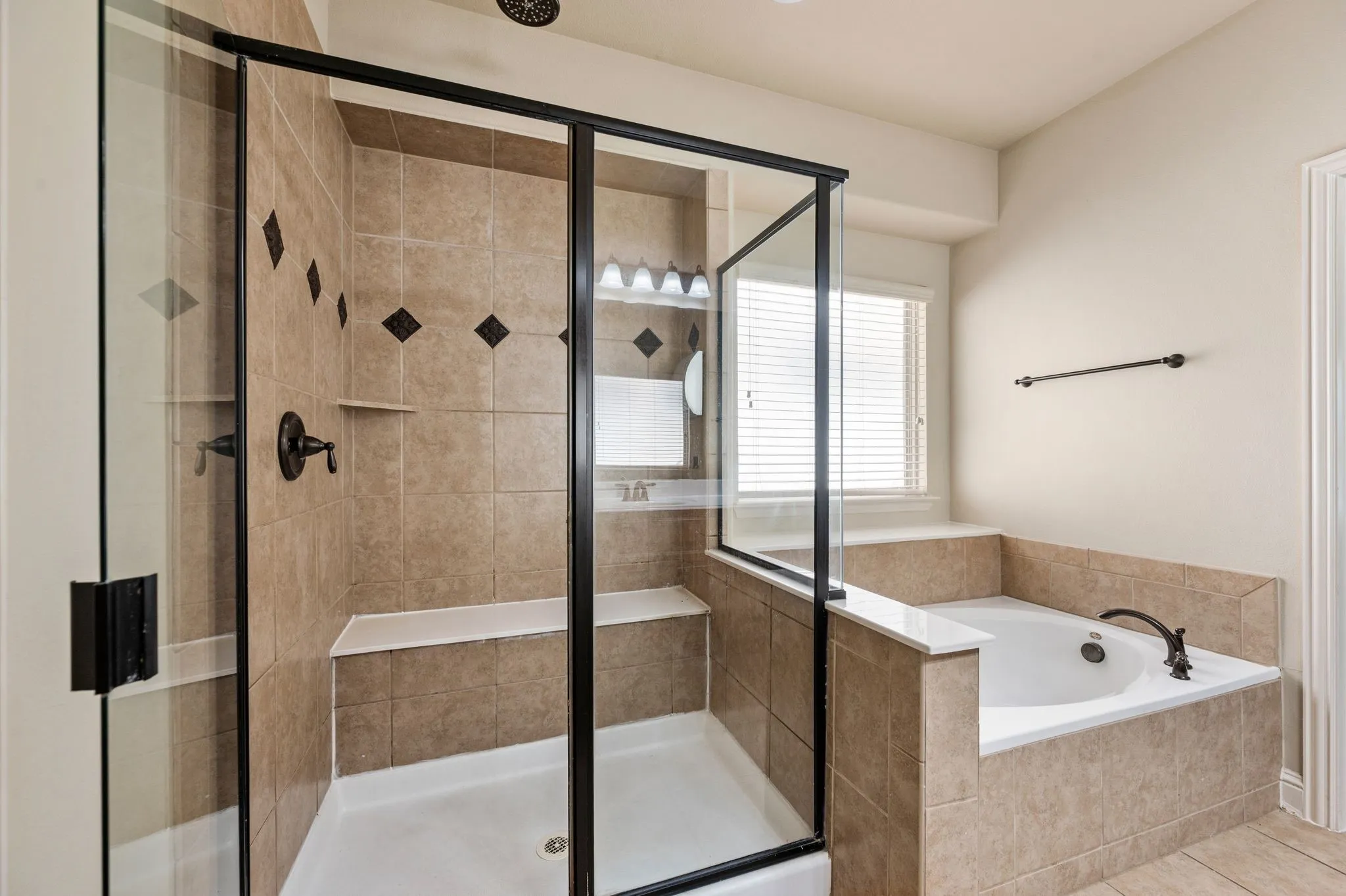 Tiled shower with a built-in bench and glass enclosure, featuring oil-rubbed bronze fixtures