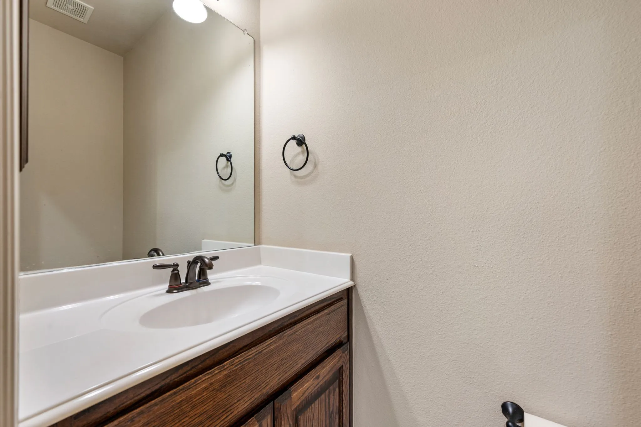 Powder bath featuring a vanity with a built-in basin, white countertop, and dark wood-finish cabinetry